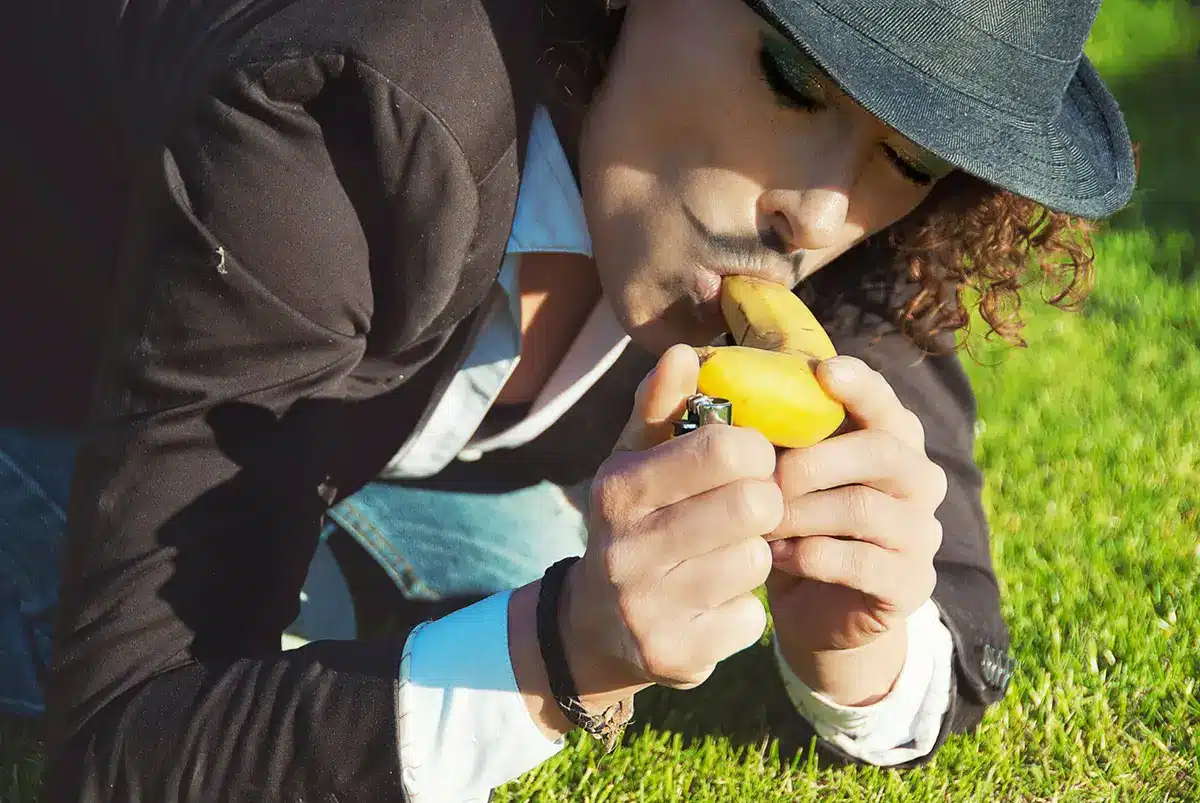 Girl wearing a hat lighting a banana with a lighter like a cigaro