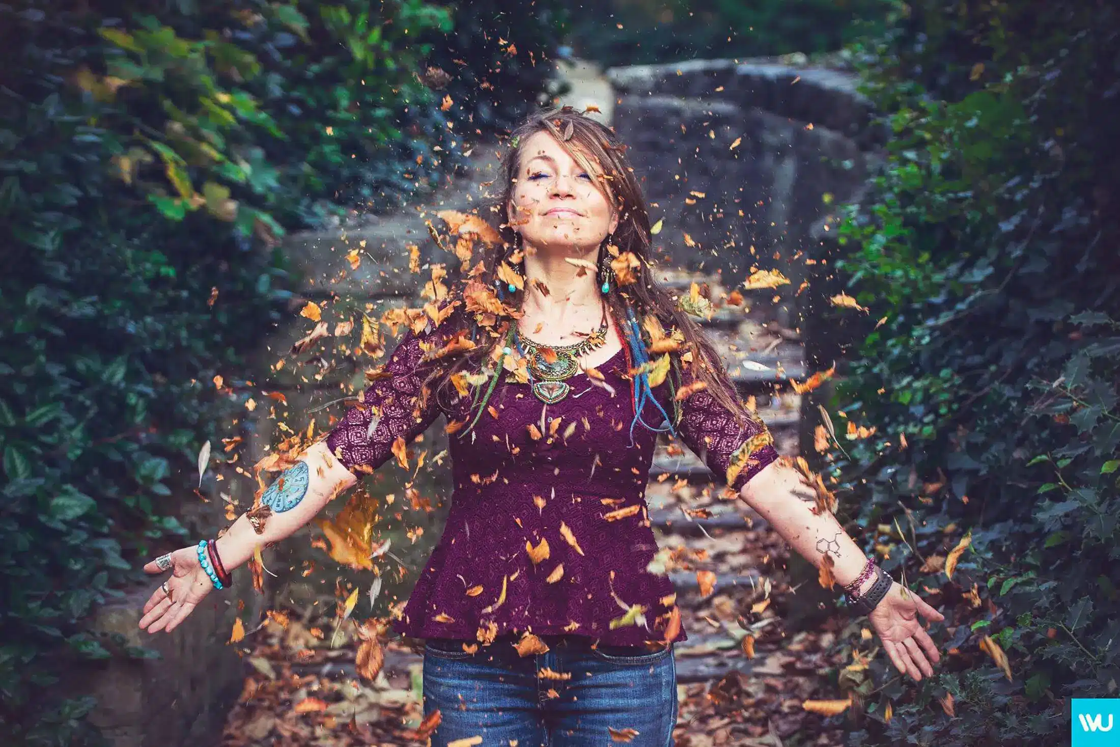 Colourful portrait of a woman throwing autumn leaves into the air